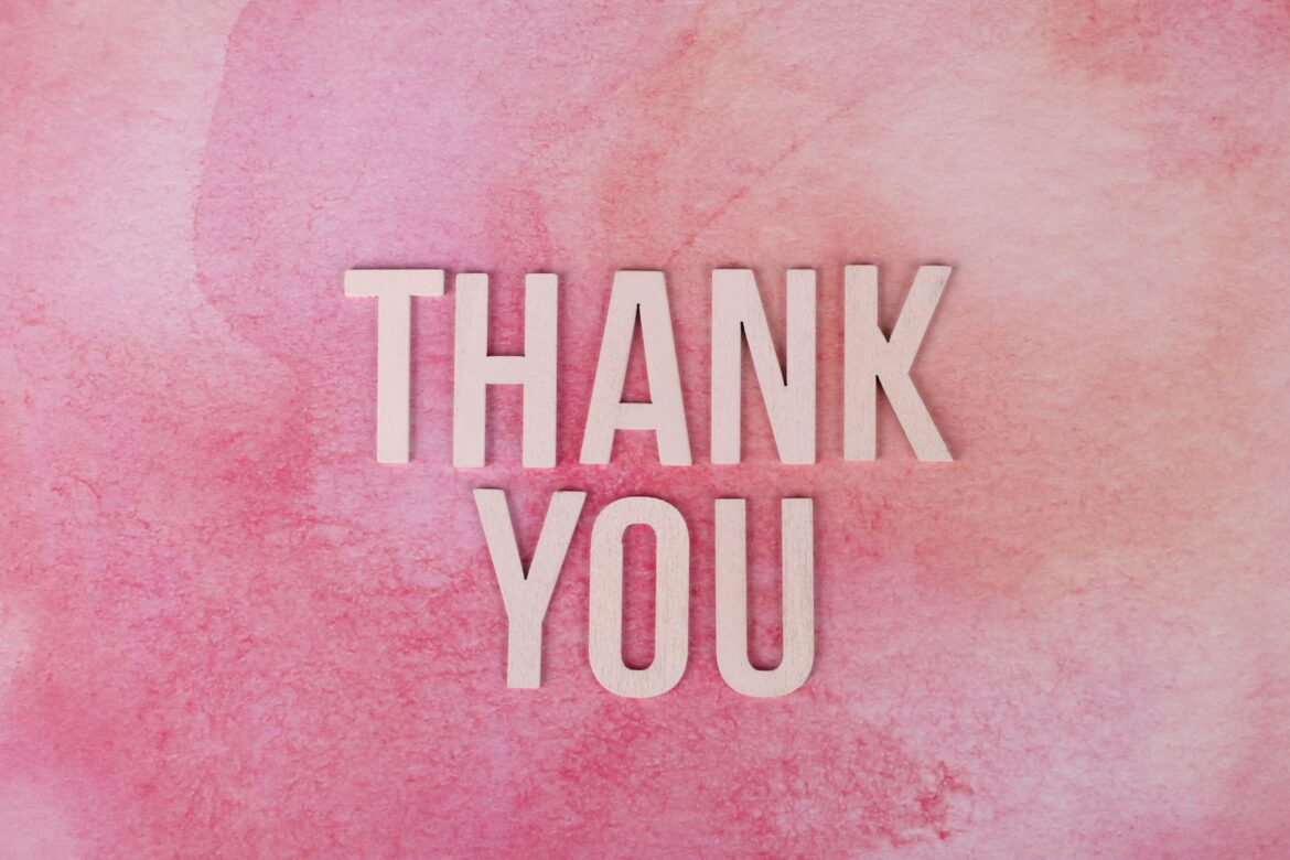 Express gratitude creatively with this 'Thank You' design featuring wooden letters on a pink background.