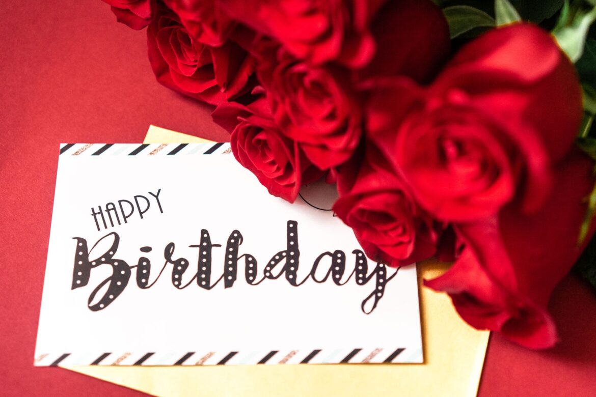 A stylish birthday card surrounded by vibrant red roses on a red background.