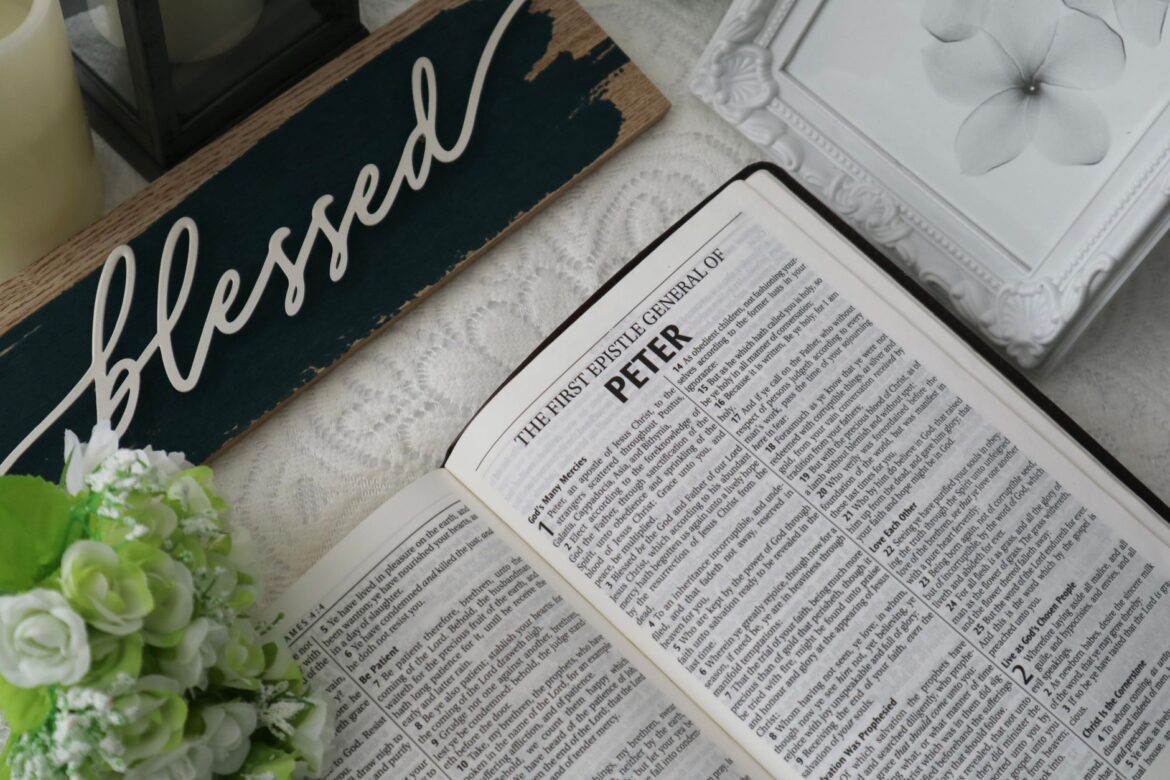 Top view of an open Bible with a 'blessed' sign and floral decor, conveying a serene and spiritual atmosphere.