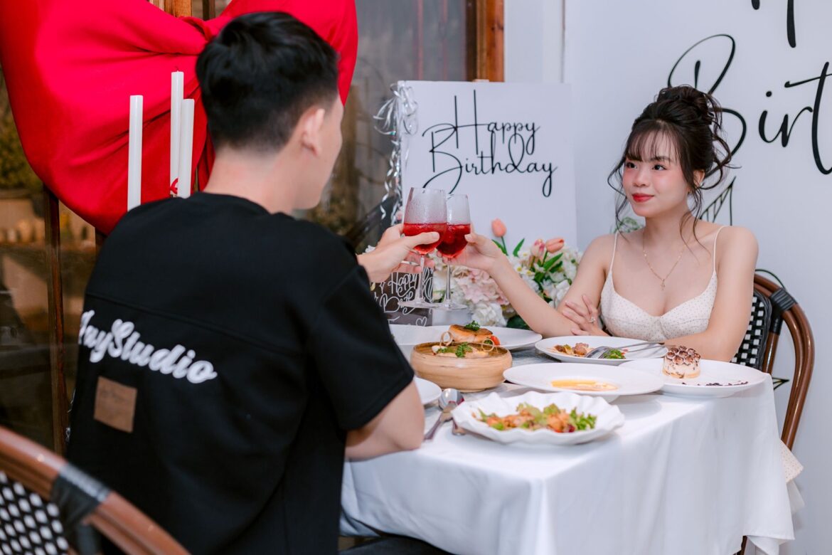 Couple toasting at a romantic birthday dinner with elegant decorations.