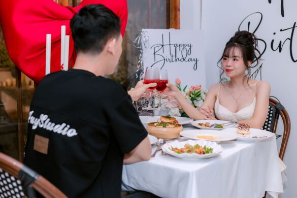 Couple toasting at a romantic birthday dinner with elegant decorations.