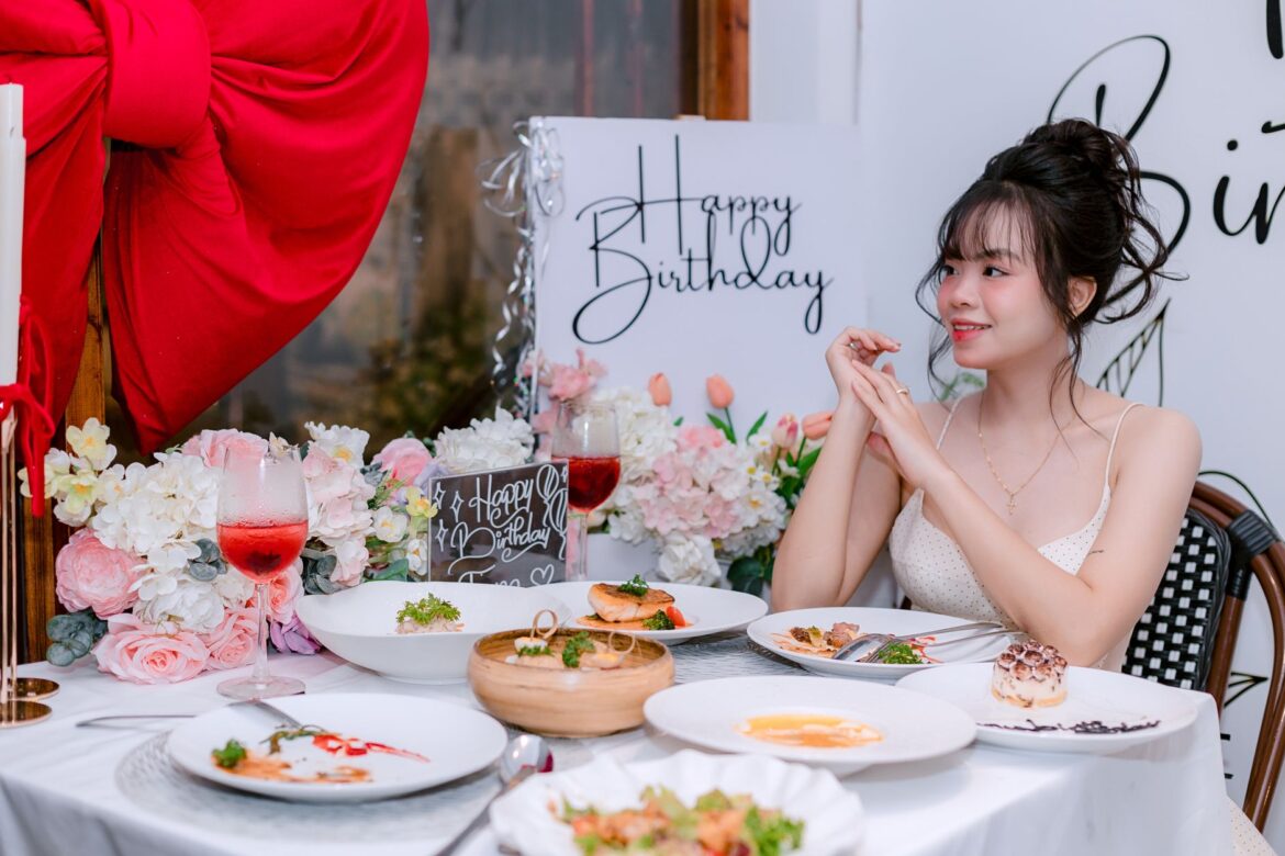 A sophisticated birthday celebration with a young woman enjoying gourmet dishes in an elegant setting.