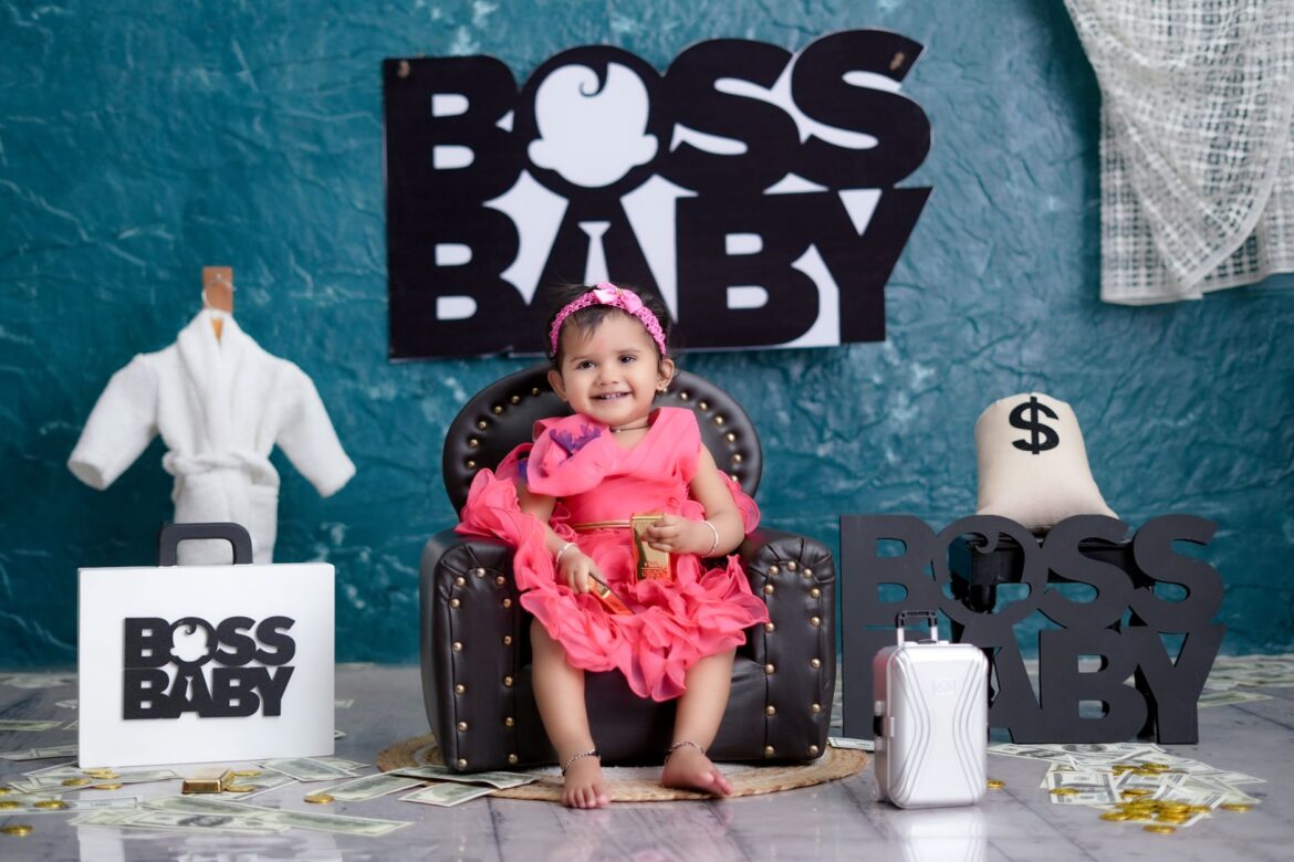 Charming baby girl in a luxurious 'Boss Baby' themed setup with decorations and props.