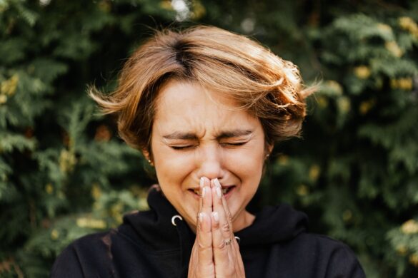A woman with closed eyes and hands folded, expressing deep emotion outdoors.