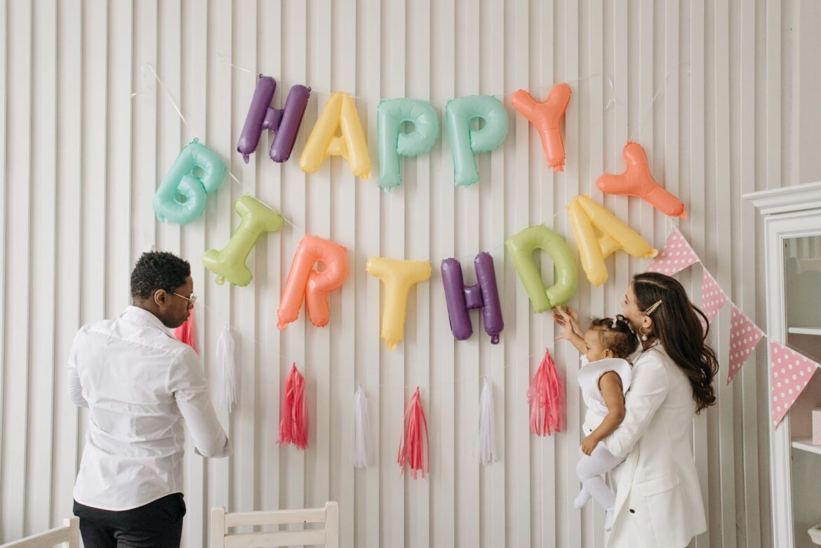 Parents decorating for their child's birthday with colorful balloons and banners.