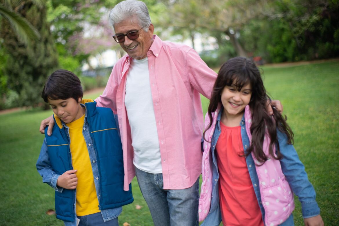 Happy grandfather bonding with grandchildren in a lush park, enjoying a joyful day outdoors.