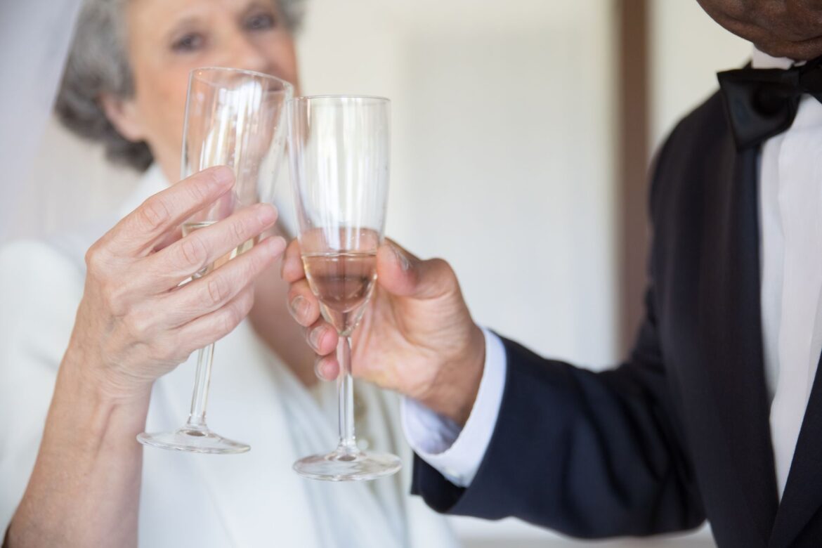 Senior couple in formal attire toasting with champagne glasses, celebrating together.