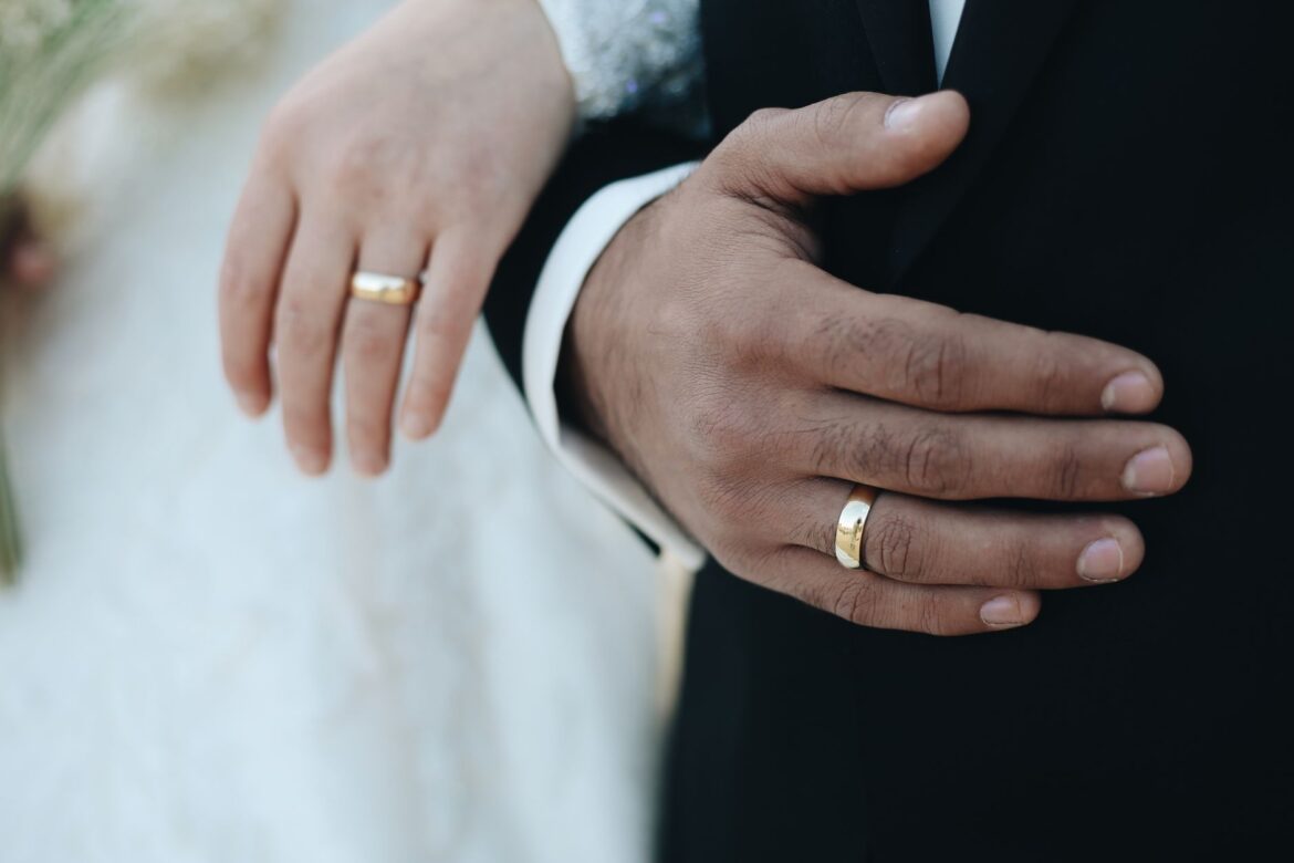 Close-up of bride and groom's hands with wedding rings, symbolizing love and commitment.