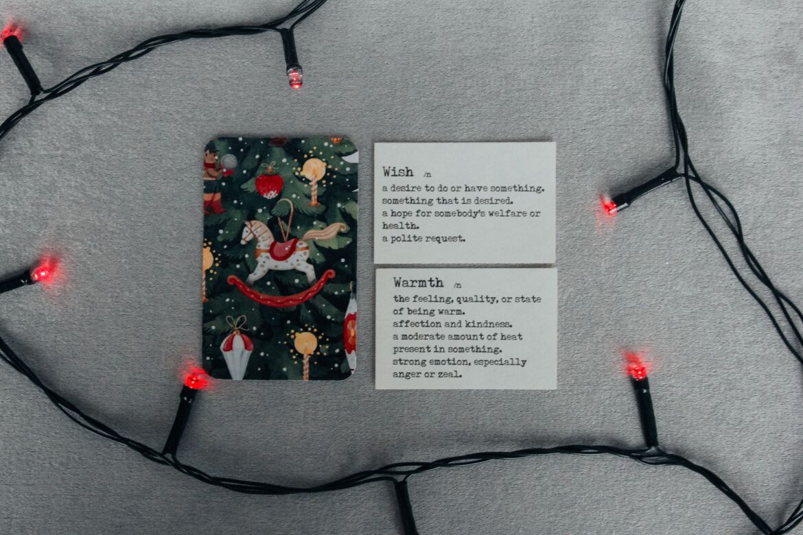 A holiday card and string lights with inspiring definitions set on a festive background.