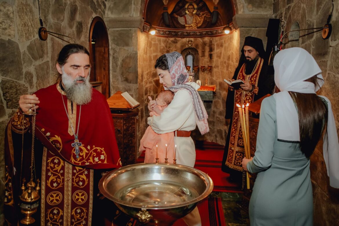 A sacred baptism ceremony inside an Orthodox church with priests and family.