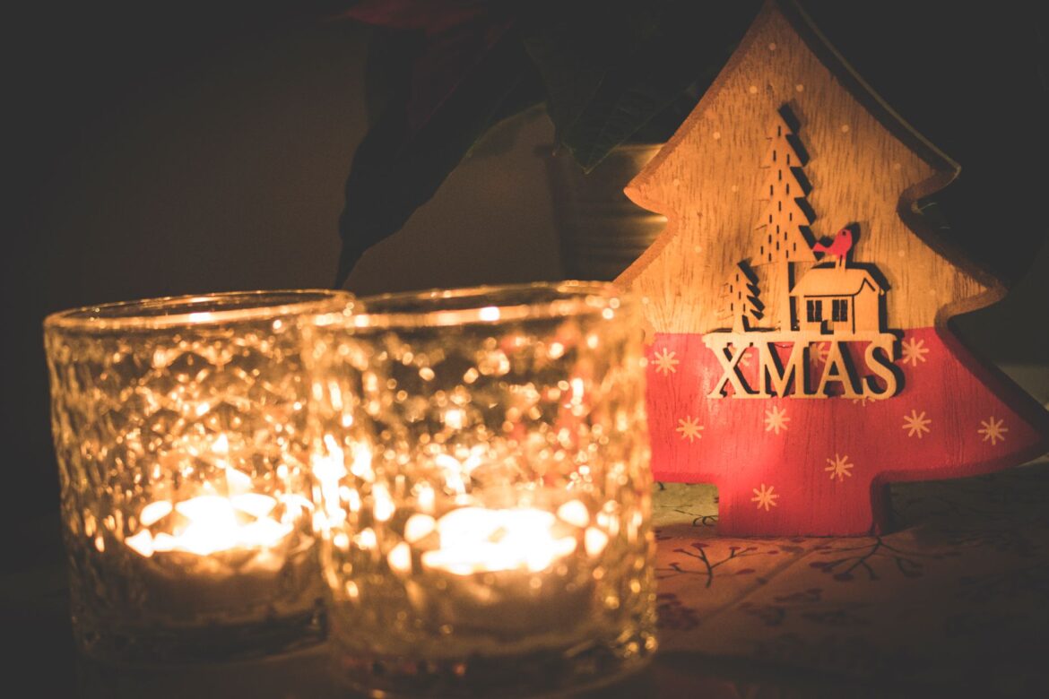 Warm Christmas scene with candles and a wooden tree decoration.
