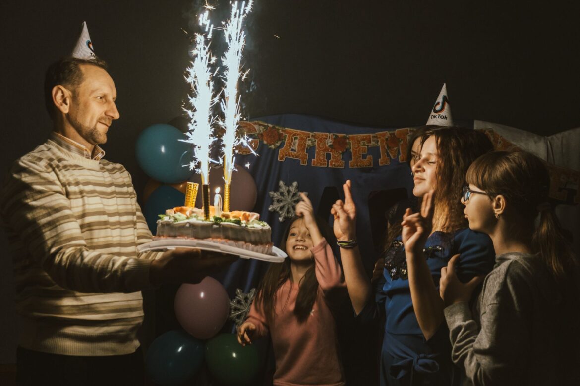A family celebrating a birthday with a sparkling cake and joyful moments indoors.