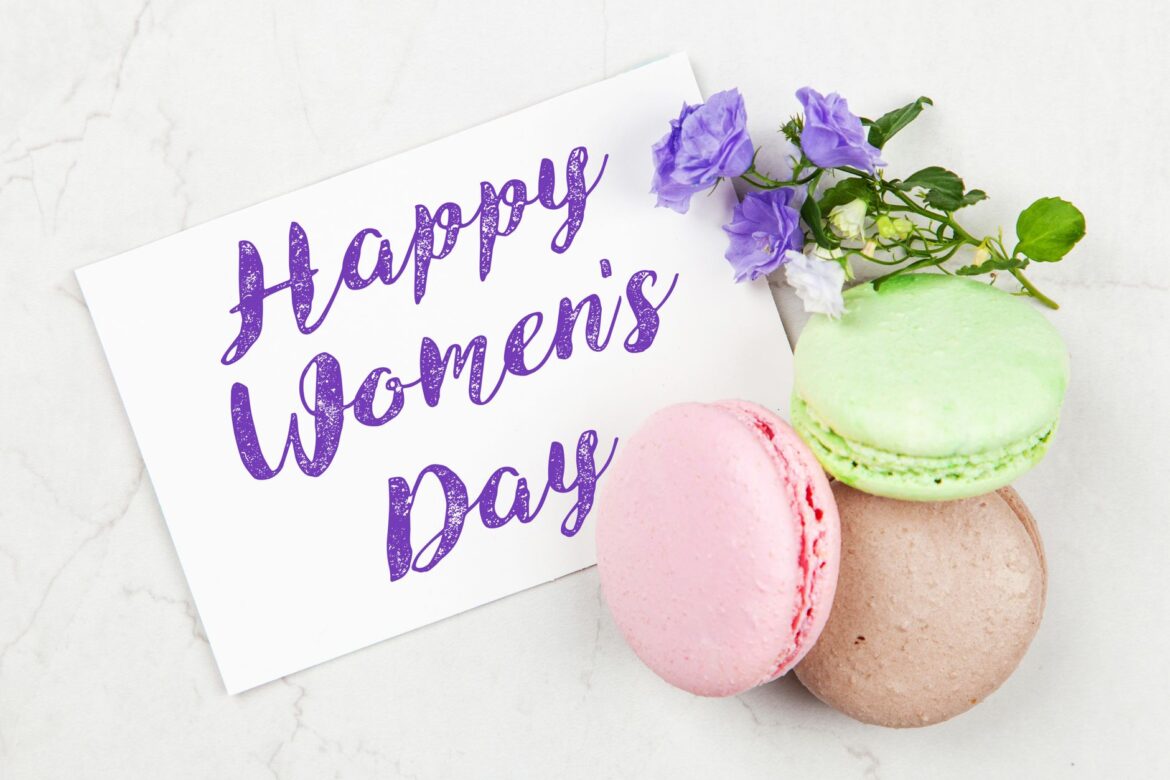 Celebrate Women's Day with a vibrant card featuring pastel macarons and purple flowers.