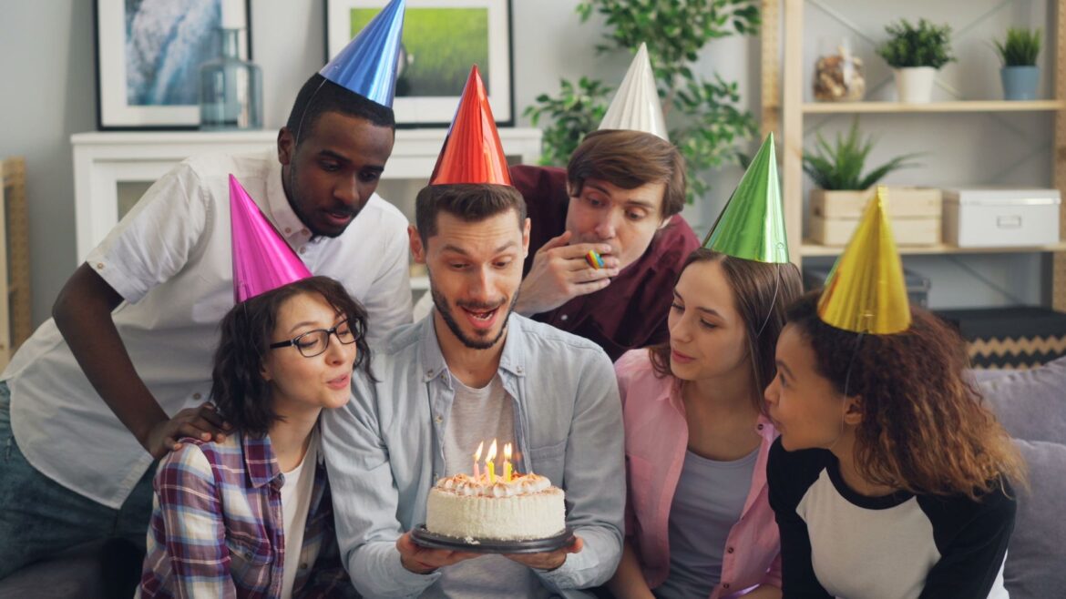 Group of friends celebrating with a birthday cake indoors.