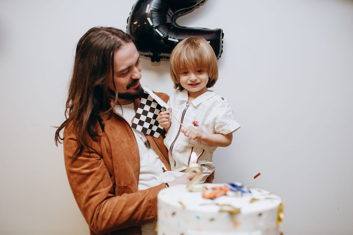 A joyful father holding his son in an indoor birthday party setting.