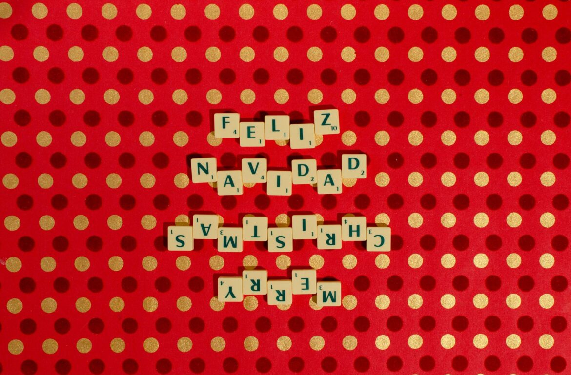 Scrabble tiles spelling 'Merry Christmas' and 'Feliz Navidad' on a red polka dot backdrop.