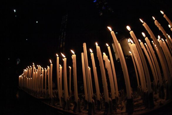A row of lit candles glowing warmly in a dark setting, creating a serene atmosphere.