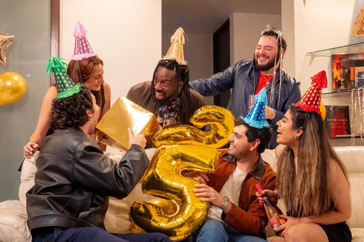 A joyous indoor birthday party with friends, featuring festive hats and gifts.