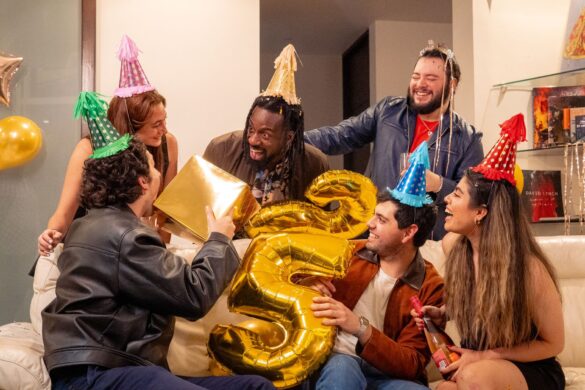 A joyous indoor birthday party with friends, featuring festive hats and gifts.