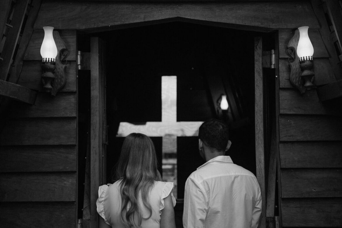 Couple seen from behind entering a church with a cross in Paragominas, Brazil.