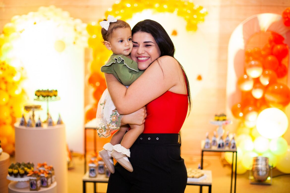 Mother and toddler enjoying a festive birthday party with colorful balloons.