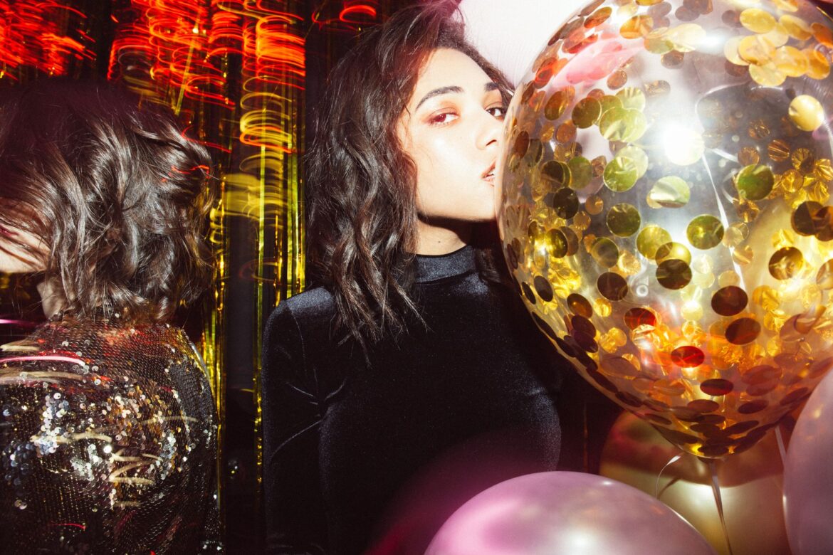 Elegant woman at a vibrant party with gold confetti balloons creates a festive atmosphere.