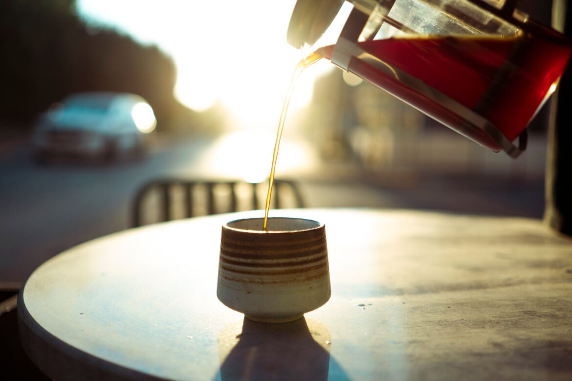 Warm morning light as coffee is poured into a cup at an outdoor cafe table in Baghdad.