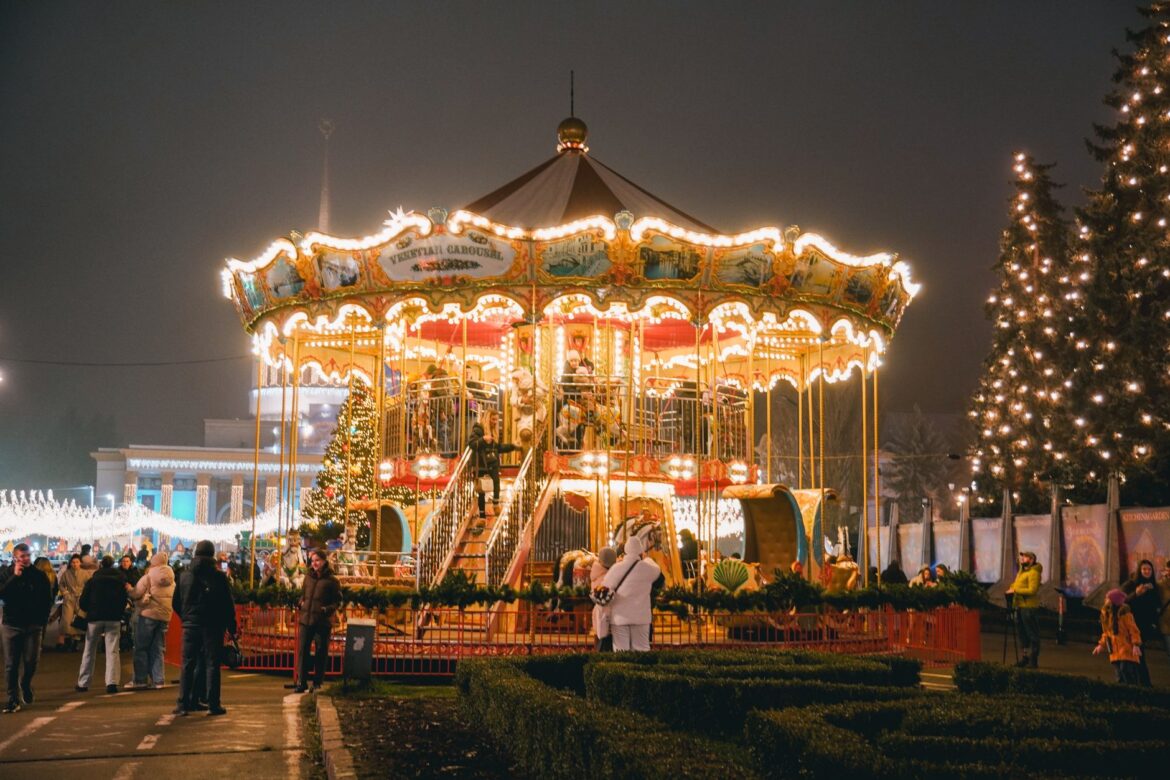A vibrant Christmas carousel in Kyiv, Ukraine at night, surrounded by people enjoying the holiday spirit.