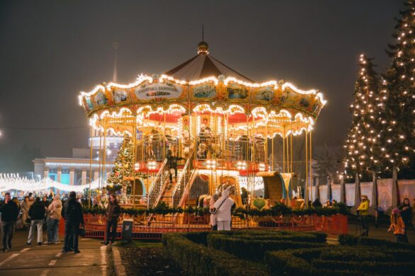 A vibrant Christmas carousel in Kyiv, Ukraine at night, surrounded by people enjoying the holiday spirit.