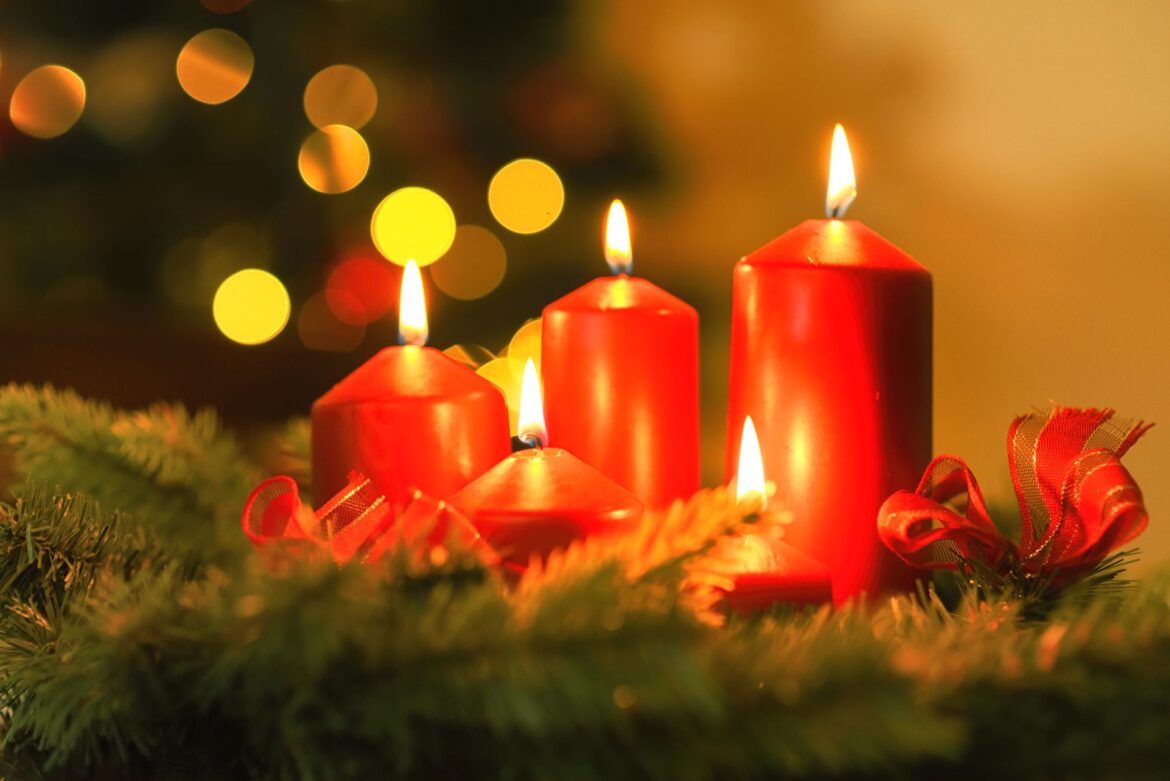 Warm and festive red candles surrounded by Christmas decorations, perfect for holiday ambiance.