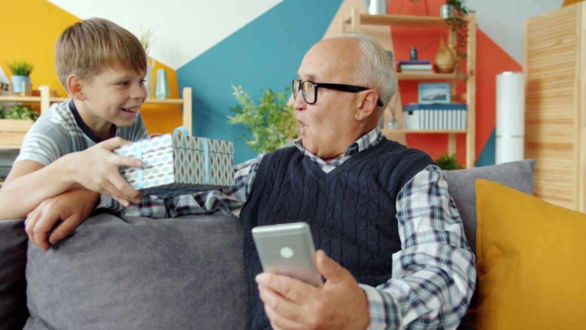 Senior man and boy enjoying a heartwarming gift exchange indoors.