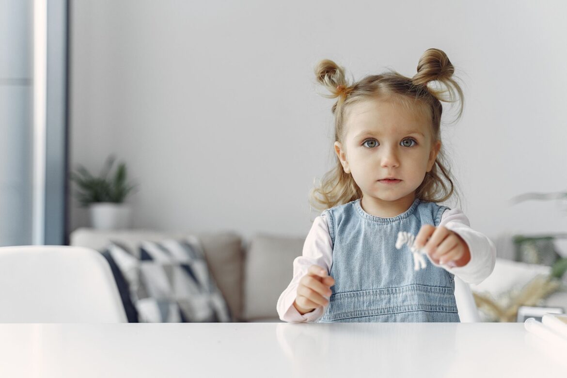 Cute child with hairstyle playing with a toy indoors, showing joy and curiosity.