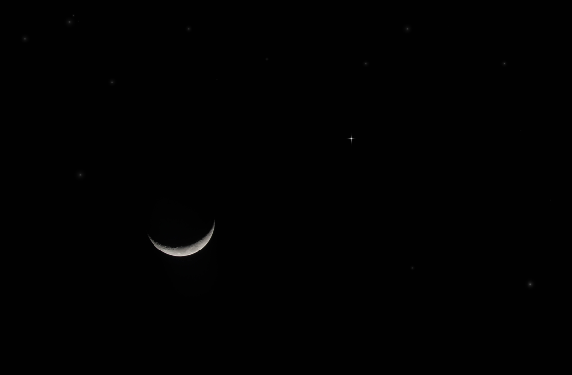 Serene night sky with a crescent moon and stars shining bright.