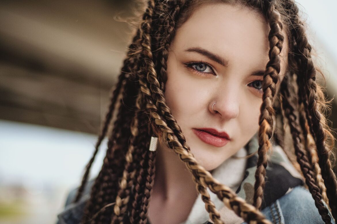 Captivating close-up of a woman with braided hair and nose piercing.