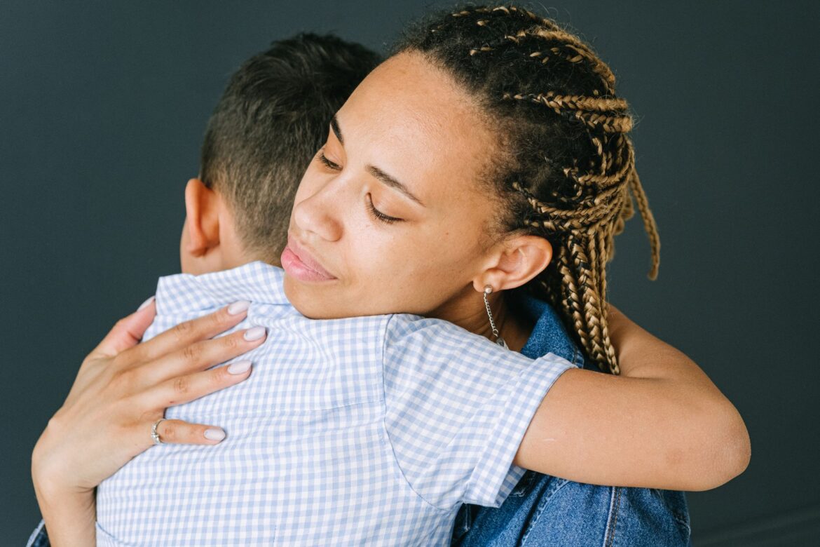 A loving mother holding and comforting her son in an emotional embrace indoors.