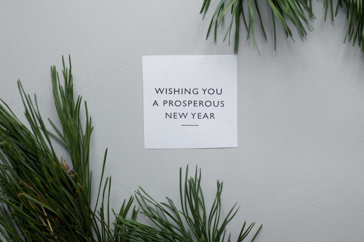 Top view of greeting card with Wishing You A Prosperous New Year text placed on gray background with green twigs