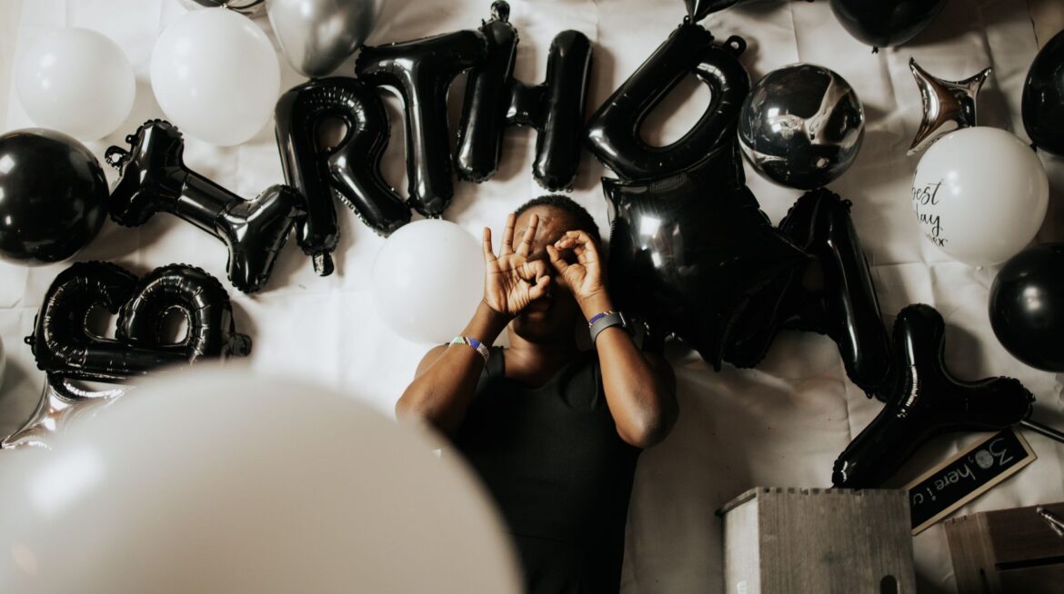 Top view of a man celebrating birthday surrounded by black and white balloons.