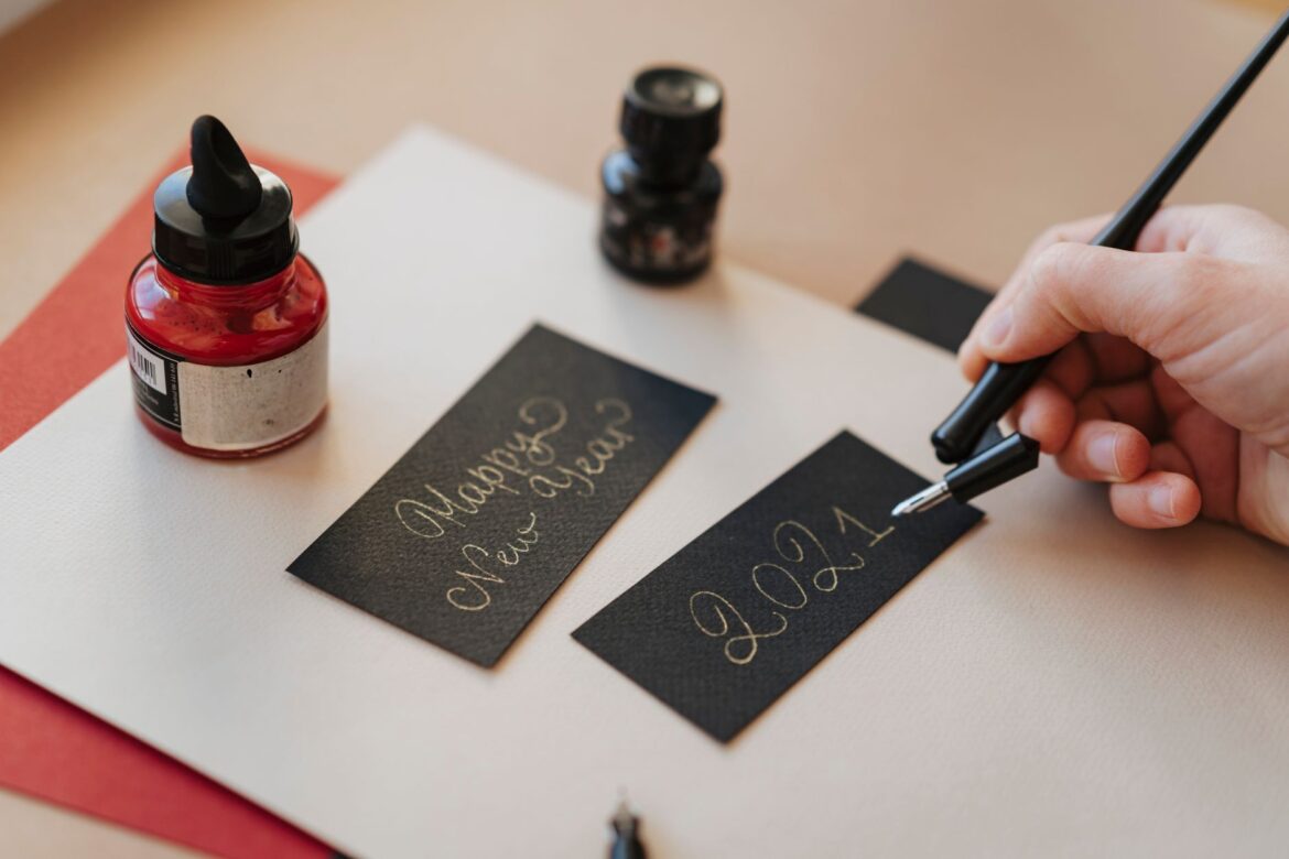 A hand writes 'Happy New Year 2021' in calligraphy with a fountain pen.