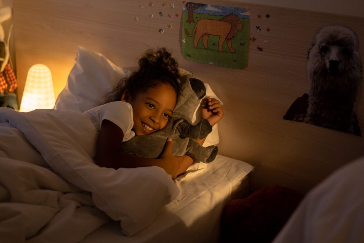Young girl cuddles with her stuffed toy in a warmly lit bedroom, creating a serene bedtime atmosphere.