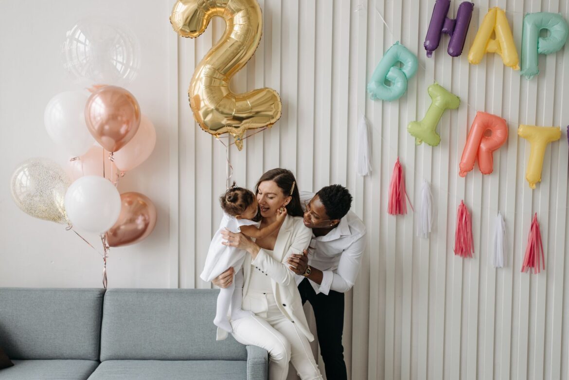 Happy family celebrating a child's birthday with balloons indoors.