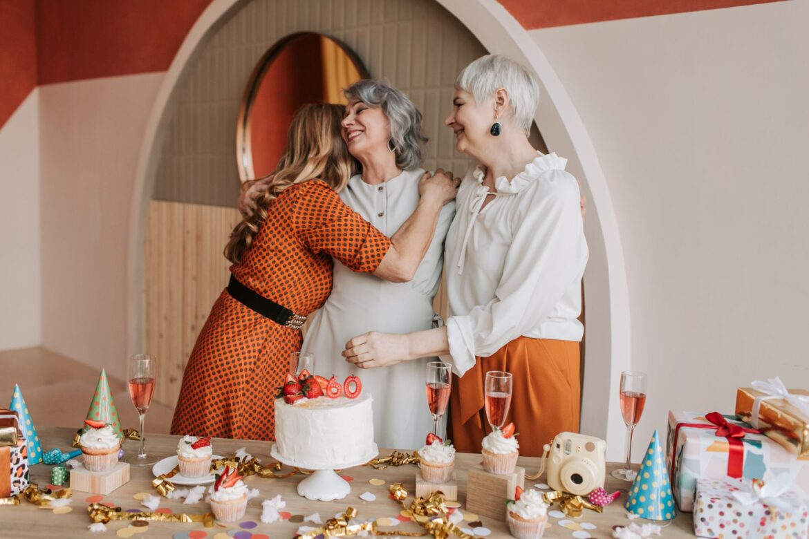 Three senior women celebrating a birthday, enjoying good company and cake indoors.