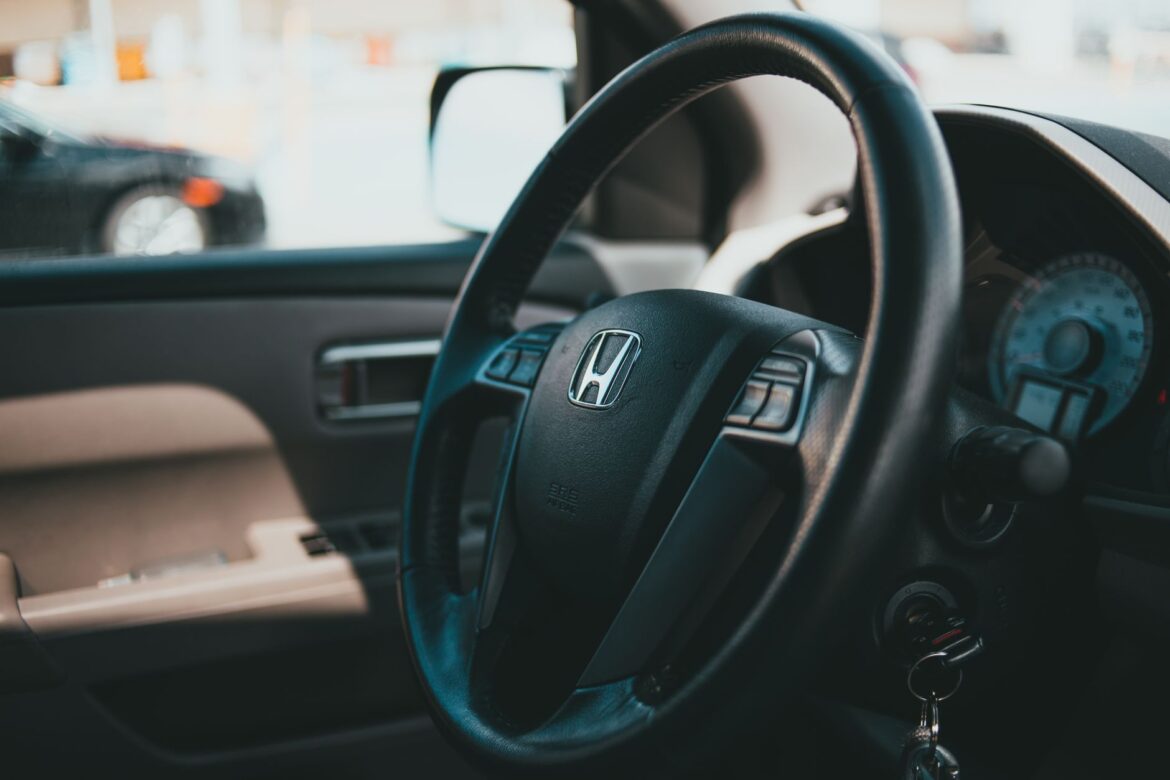 Close-up shot of a car steering wheel with dashboard, showcasing vehicle interior details.