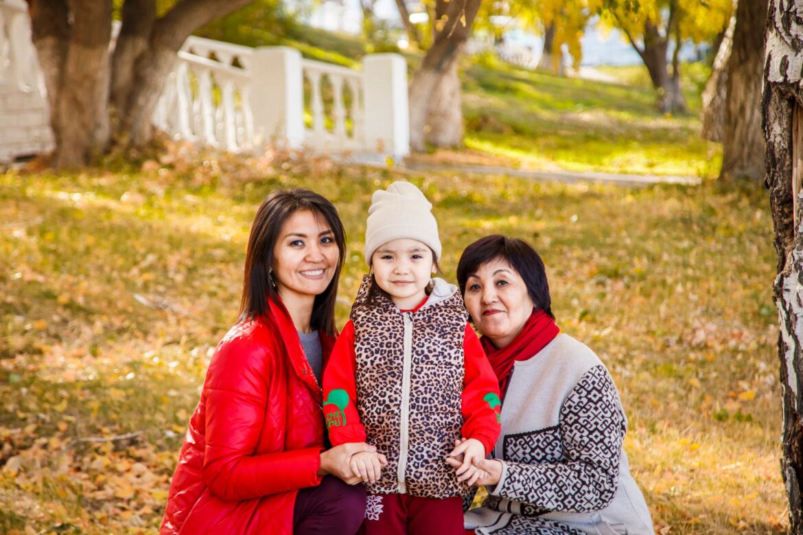 A happy family enjoying a sunny fall day outdoors, wearing jackets and smiling.