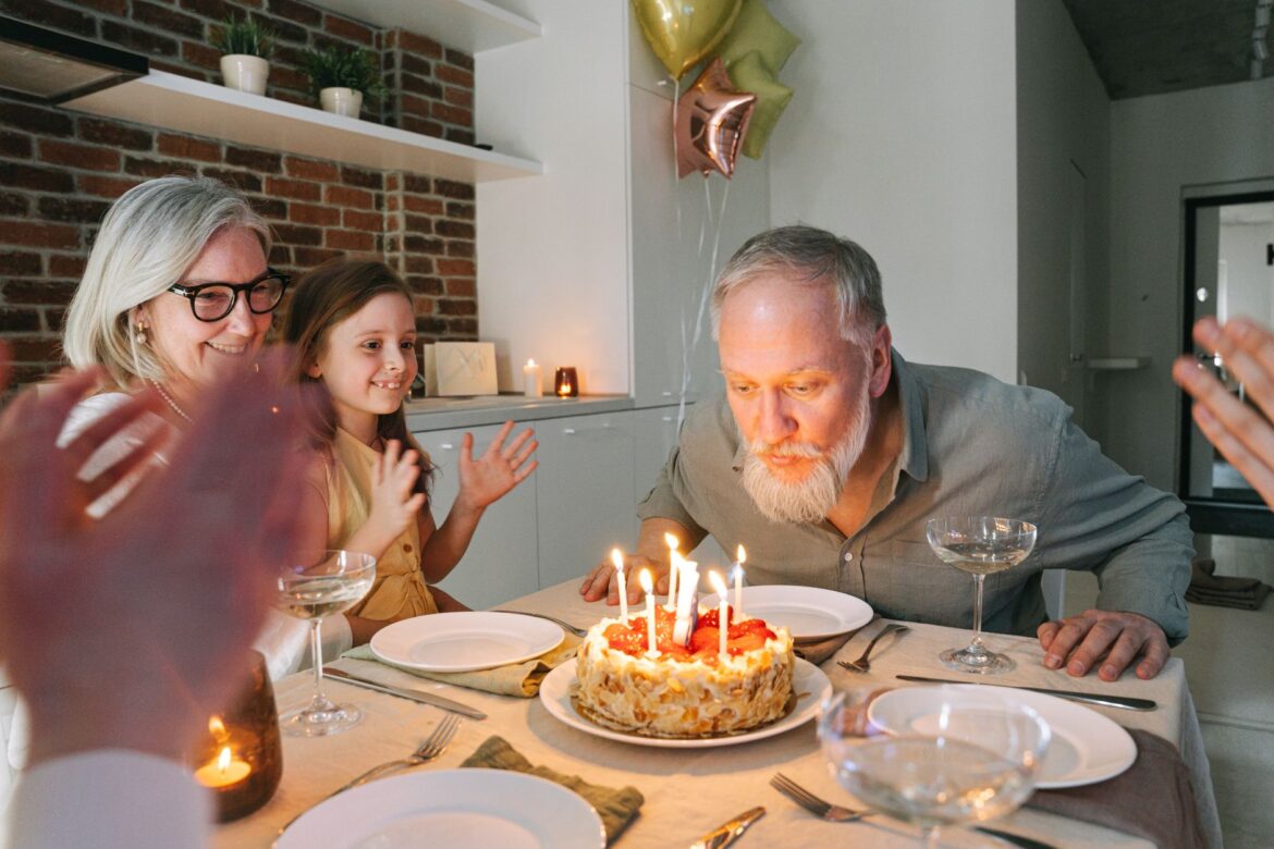 A family birthday celebration featuring a cake with lit candles and joyful togetherness.