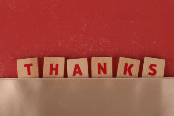 Wooden tiles with red letters spell 'Thanks', set against a red backdrop with a beige strip.